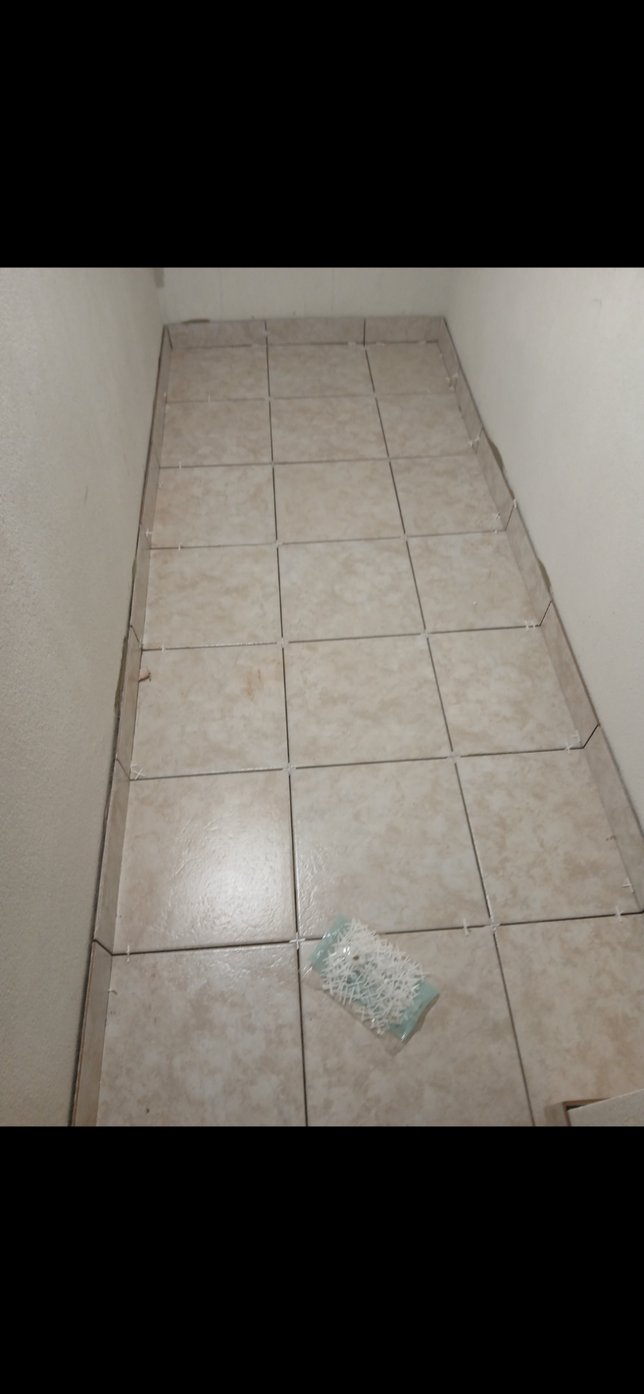 Leerer Raum mit gefliesten Boden und einem Stück Papier in der Mitte.