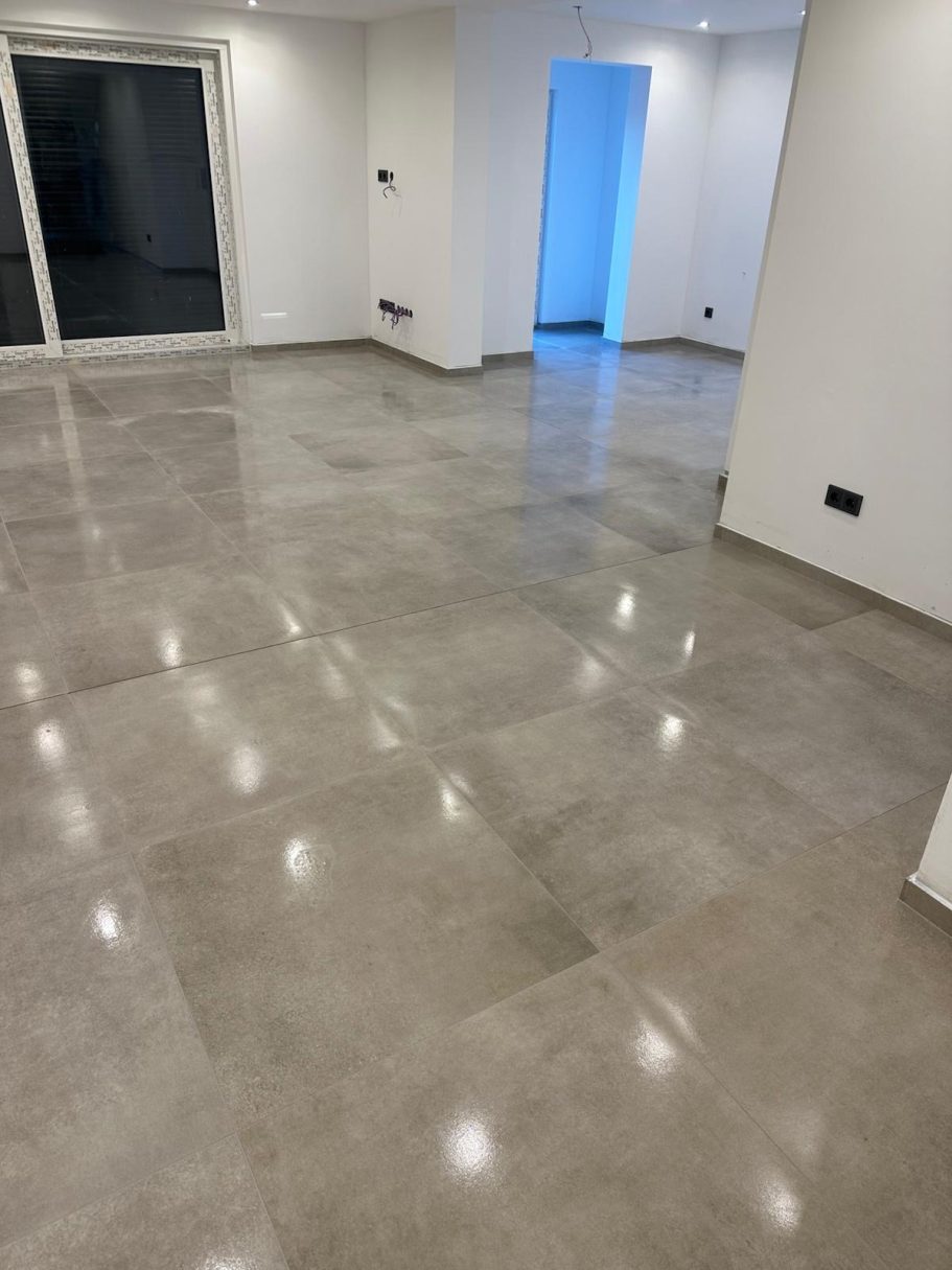 Leerer Raum mit hellen Wänden und glänzendem, grauem Bodenbelag.